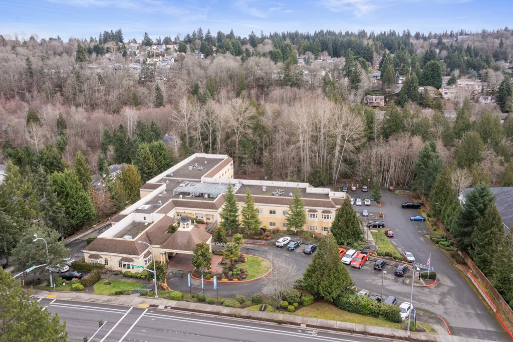 an aerial view of a building with a parking lot and trees