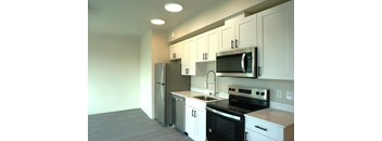A kitchen with white cabinets and black appliances.