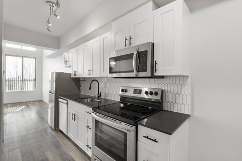 A modern kitchen with white cabinets and black countertops.