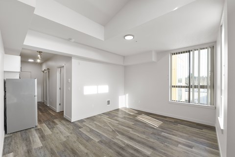 A spacious room with wooden flooring and white walls.