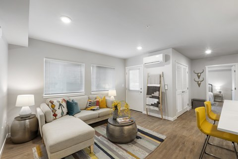 A living room with a white couch, a yellow chair, and a rug.