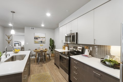 A modern kitchen with white countertops and stainless steel appliances.