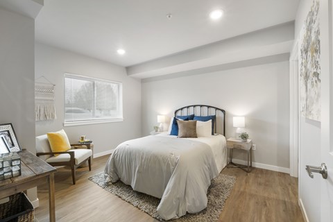 A bedroom with a large bed and a window with blinds.