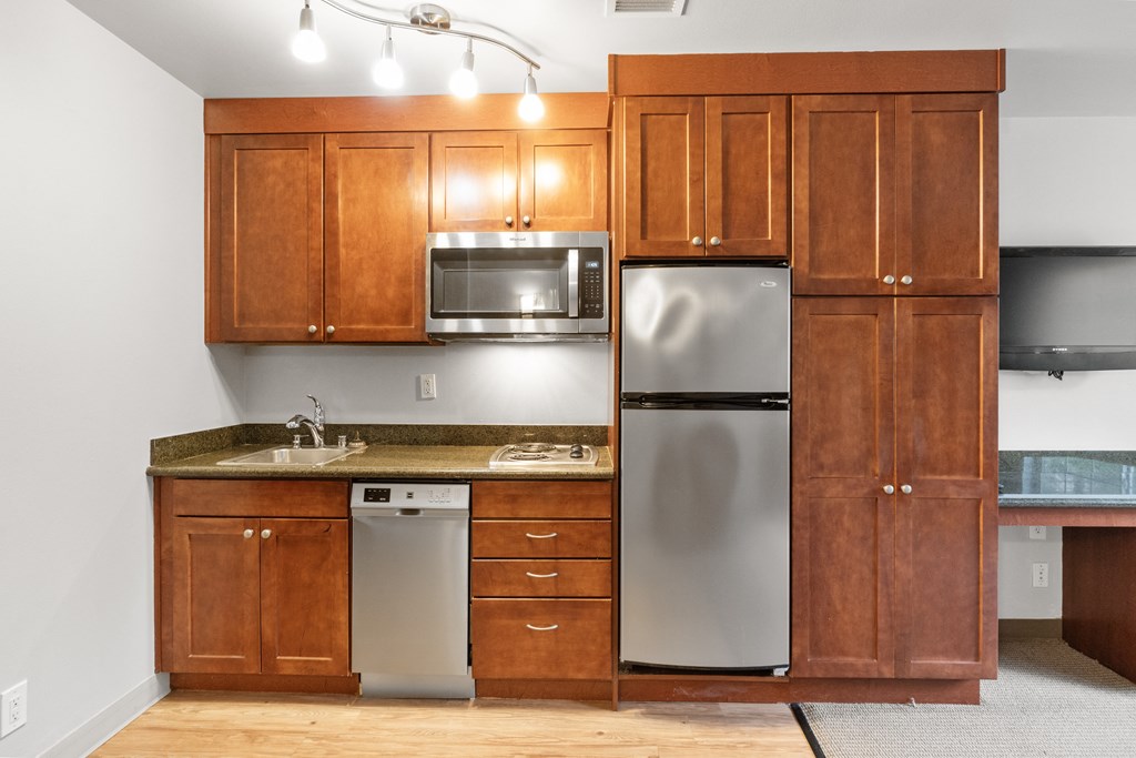 an empty kitchen with wooden cabinets and stainless steel appliances