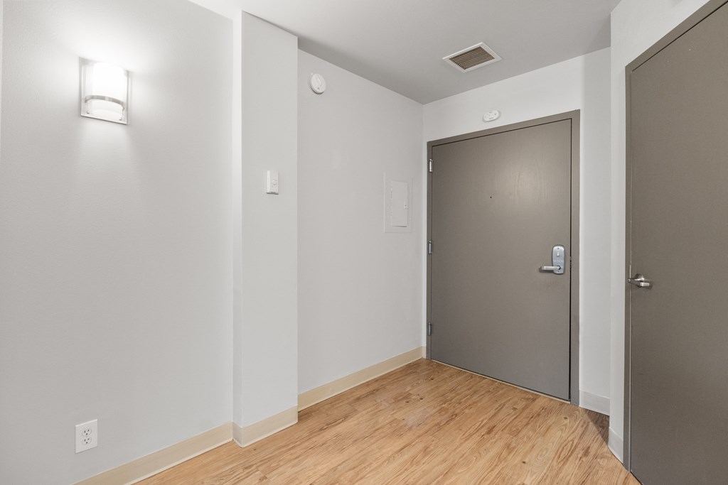 the living room of an apartment with a wood floor and a grey door