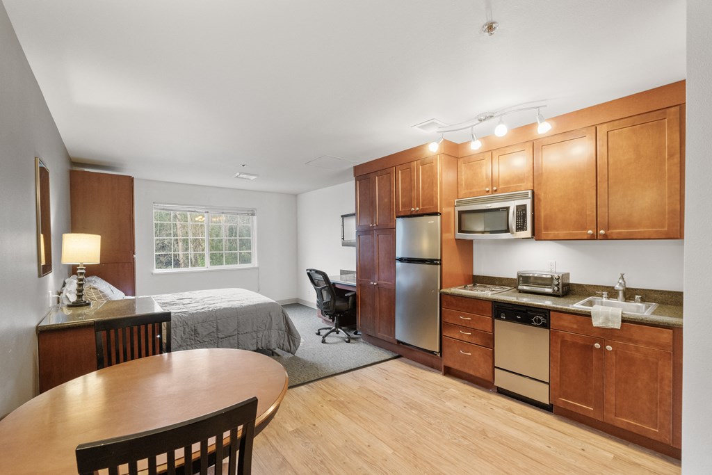 a room with a kitchen and a dining table and a bed