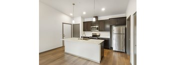 A modern kitchen with a white island and stainless steel appliances.