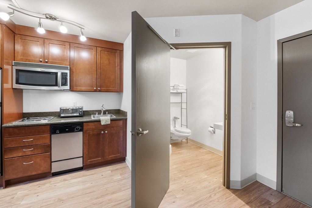 a kitchen with wooden cabinets and stainless steel appliances and a door to a bathroom