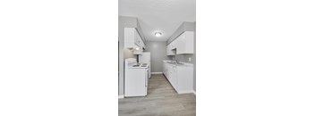 A white kitchen with a stove, oven, and sink.