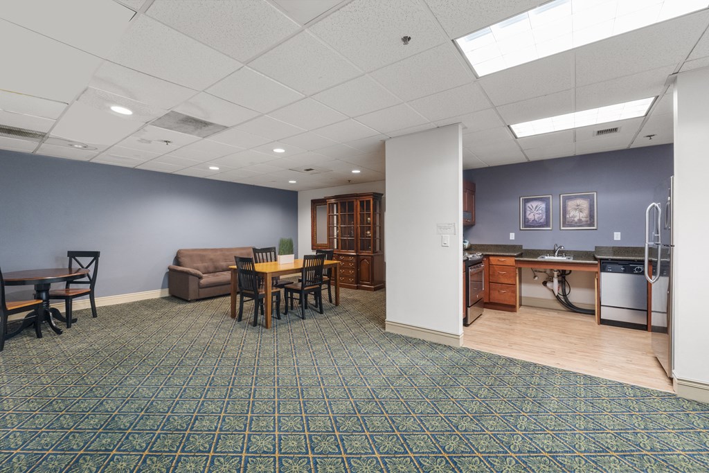 a community room with a kitchen and a table and chairs