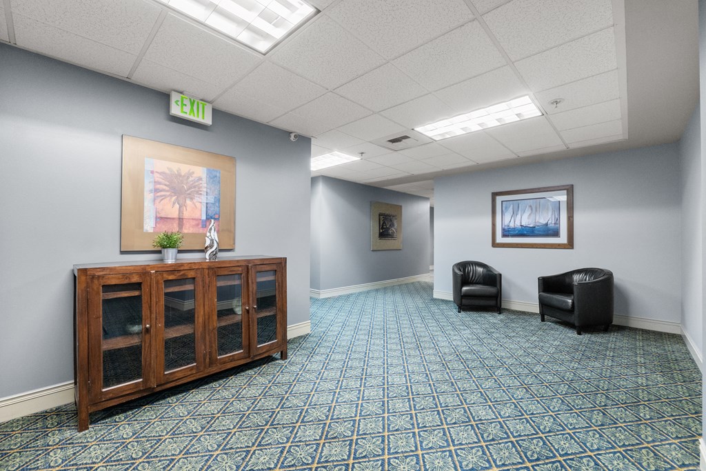 an empty waiting room with a cabinet and two chairs