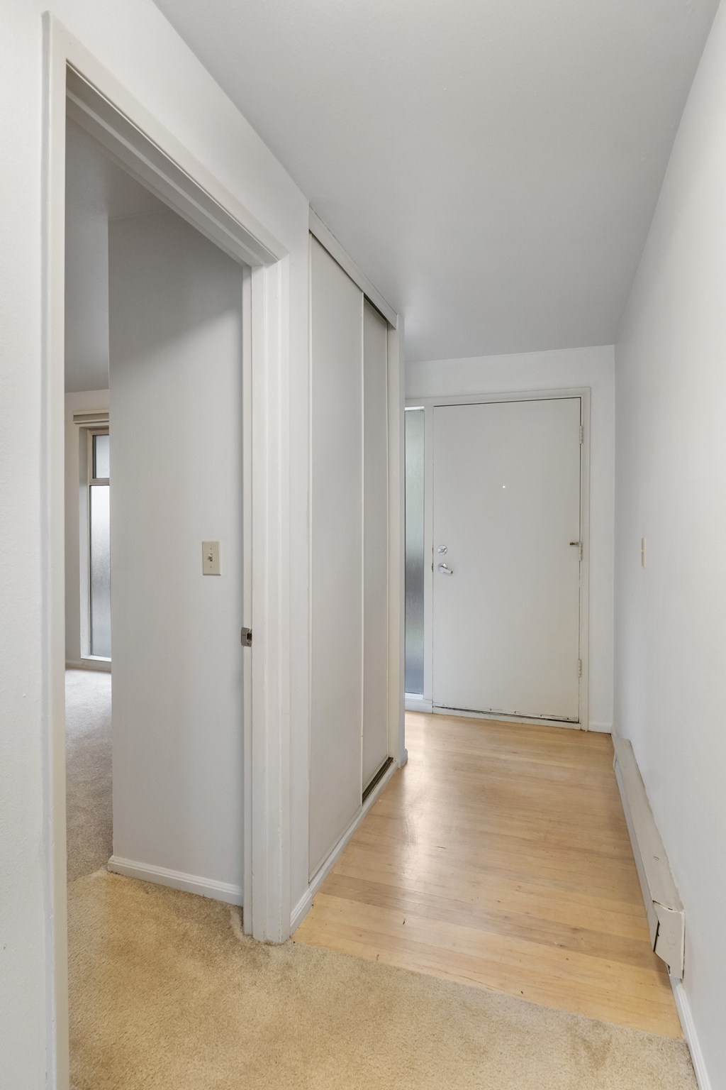 a room with white walls and a wooden floor and a closet