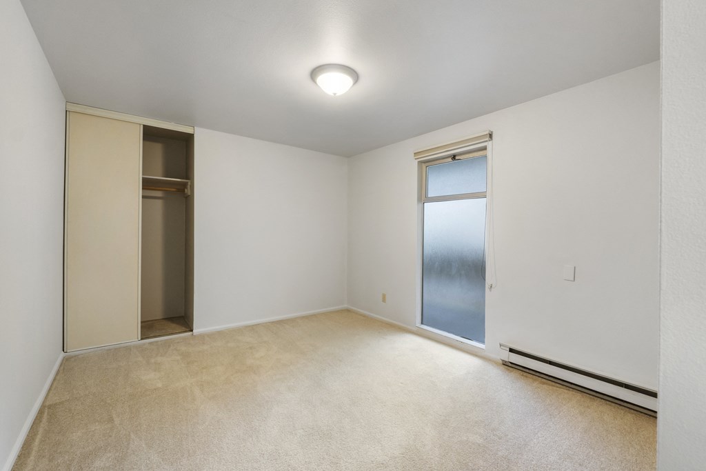 an empty living room with a sliding glass door to a closet