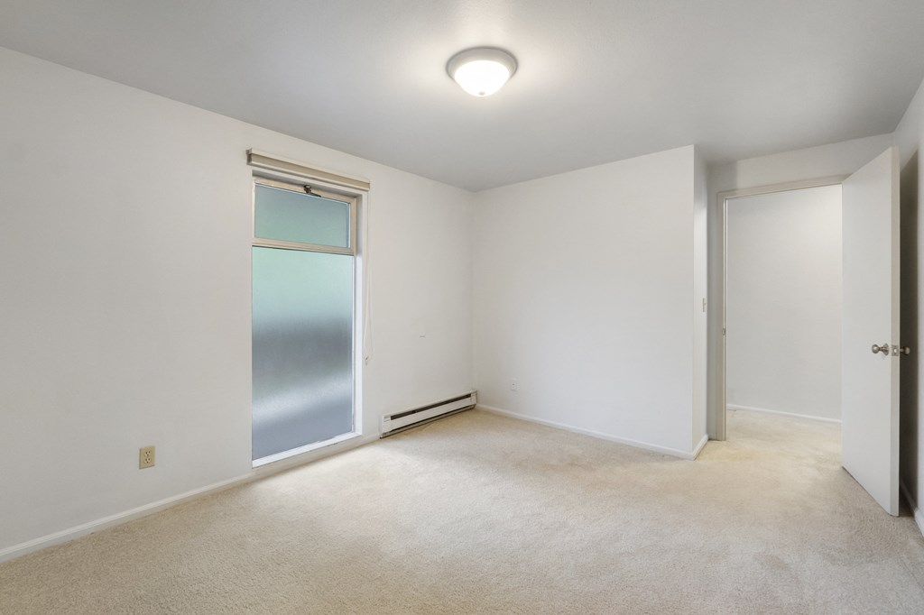 an empty room with white walls and a sliding glass door