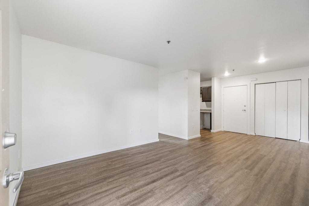 an empty living room with white walls and wood flooring