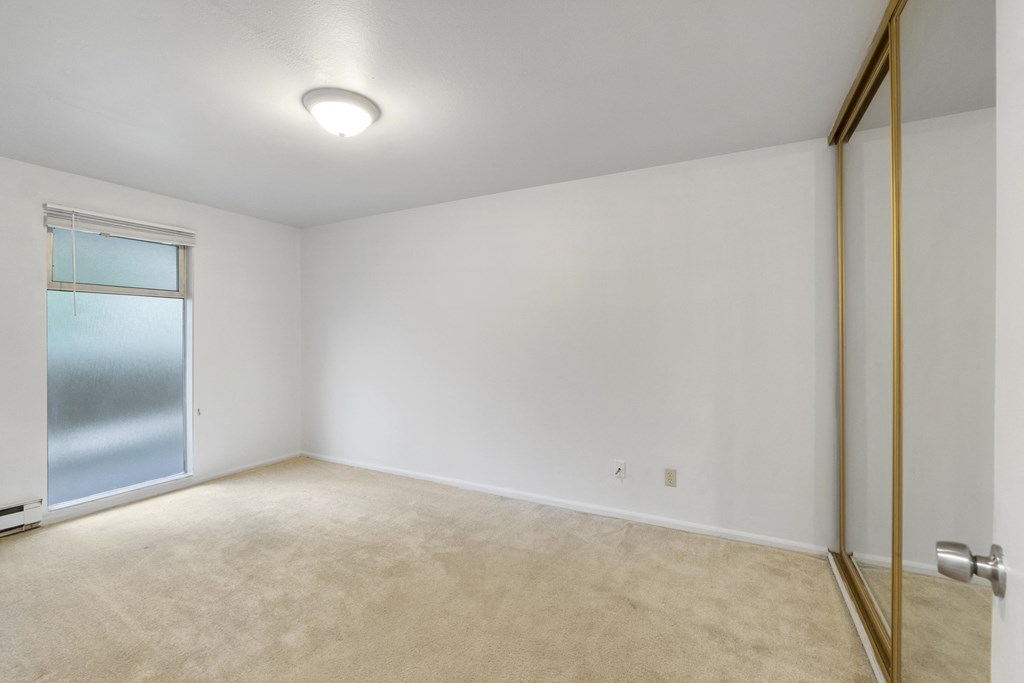 an empty living room with a sliding glass door to a closet