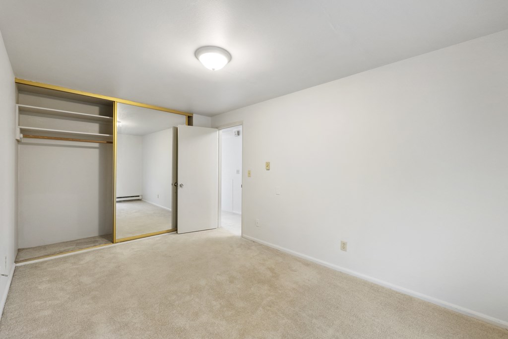 a living room with white walls and a door to a closet