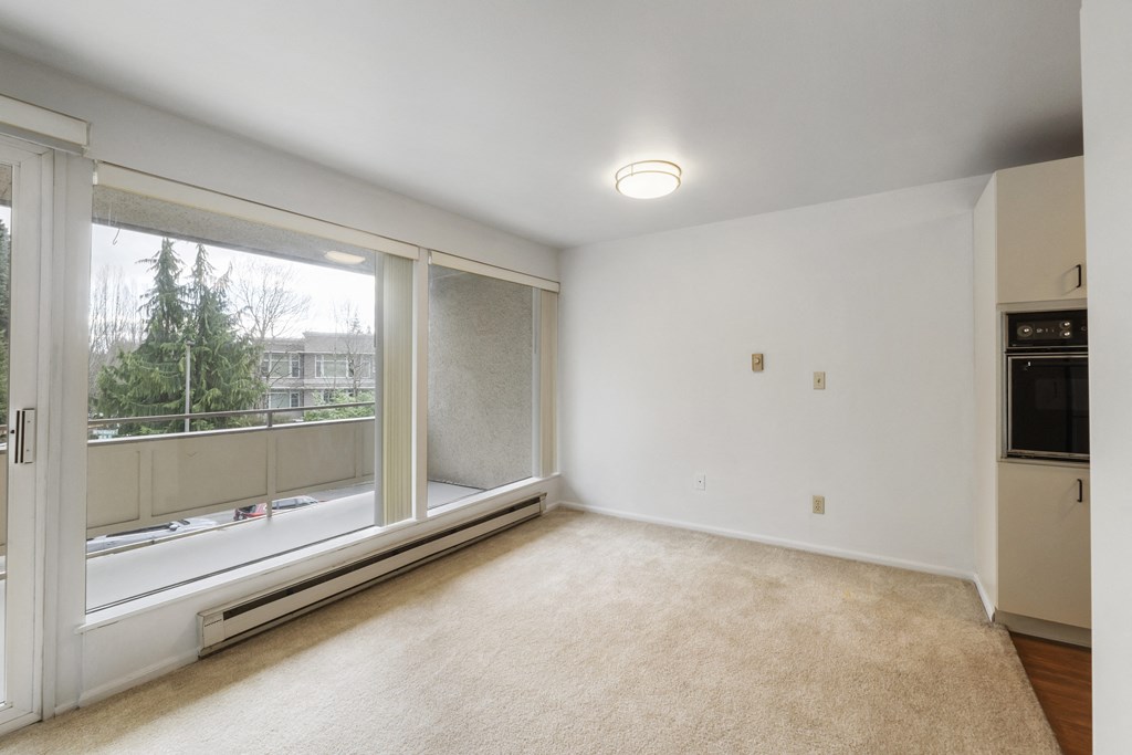 an empty living room with a large window and white walls