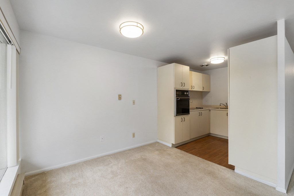 an empty living room and kitchen with white walls and wood flooring
