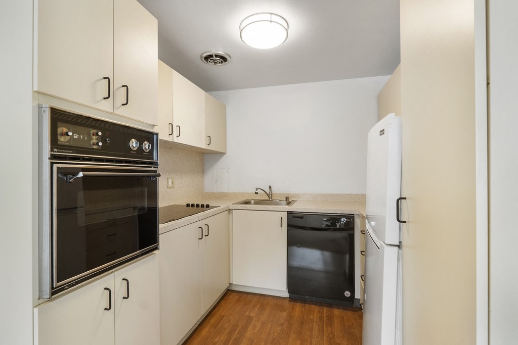 a kitchen with white cabinetry and black appliances and a refrigerator