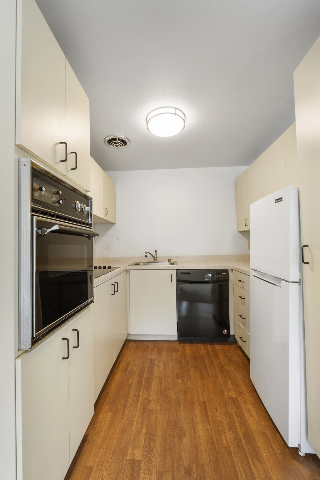 a kitchen with white cabinets and a black dishwasher and a refrigerator