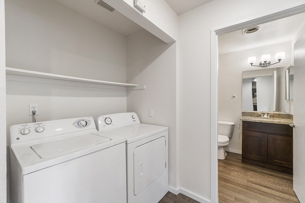 a white washer and dryer in a room with a bathroom and a toilet