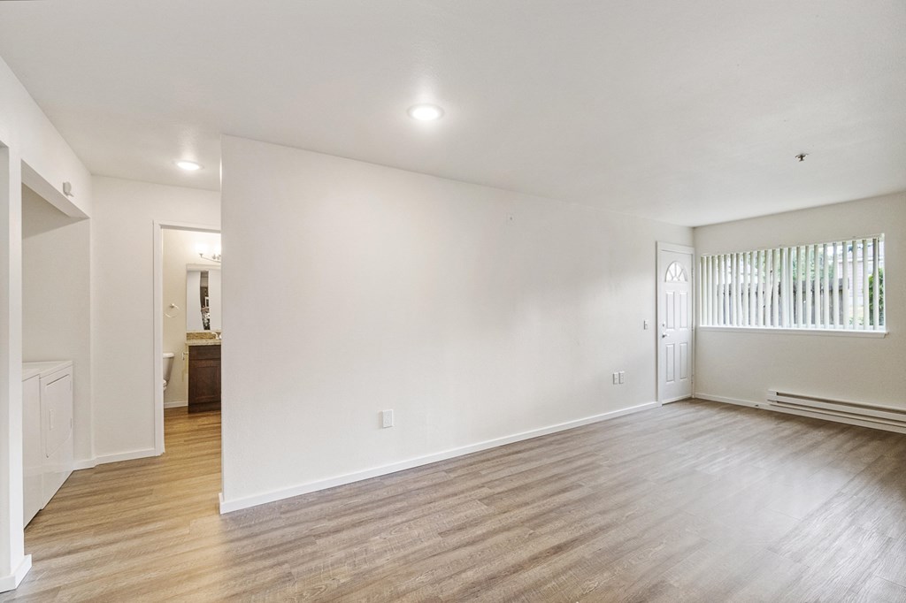 an empty living room with white walls and wood flooring