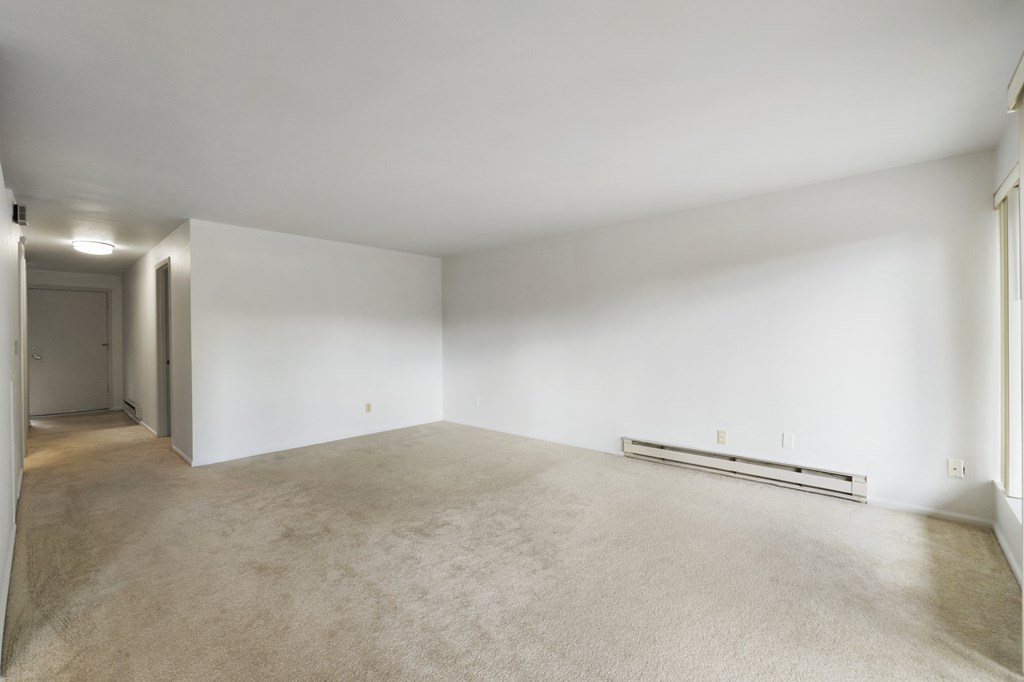 the living room and dining room of an empty house with white walls and carpet