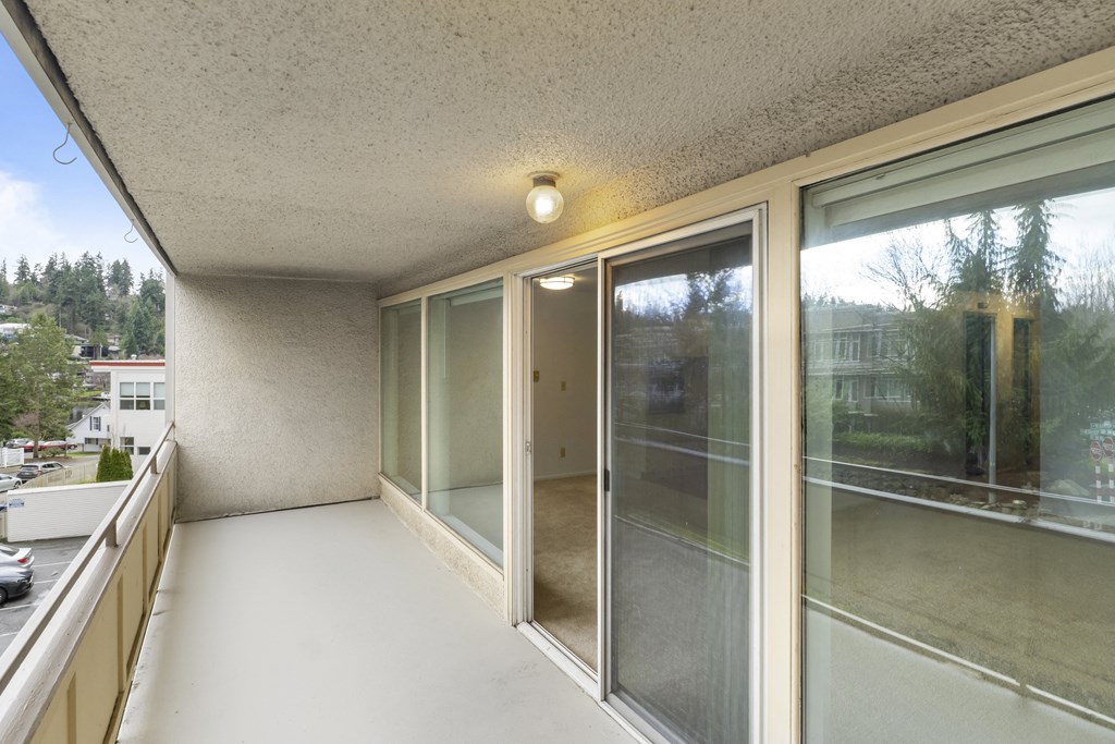the living room of a condo with large windows and a balcony
