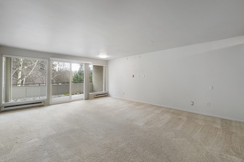 an empty living room with a large window and carpeting