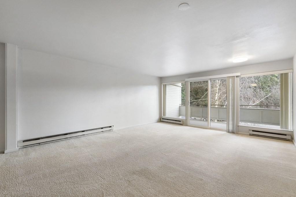 an empty living room with a large window and white walls