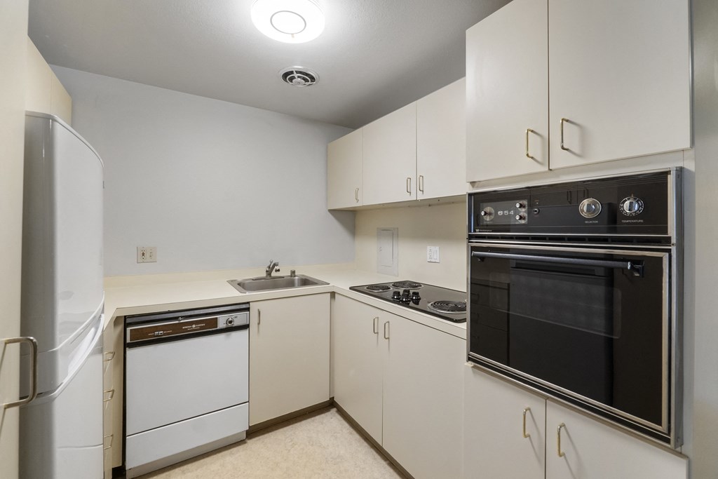 a kitchen with white cabinets and black appliances and a refrigerator