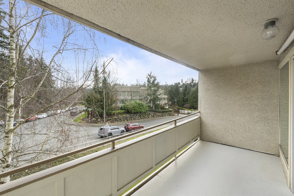 a balcony with a view of a parking lot and trees