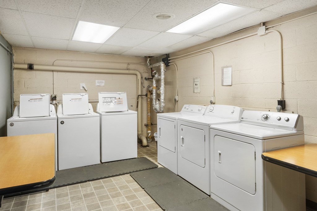 a row of washers and dryers in a laundry room with four washes