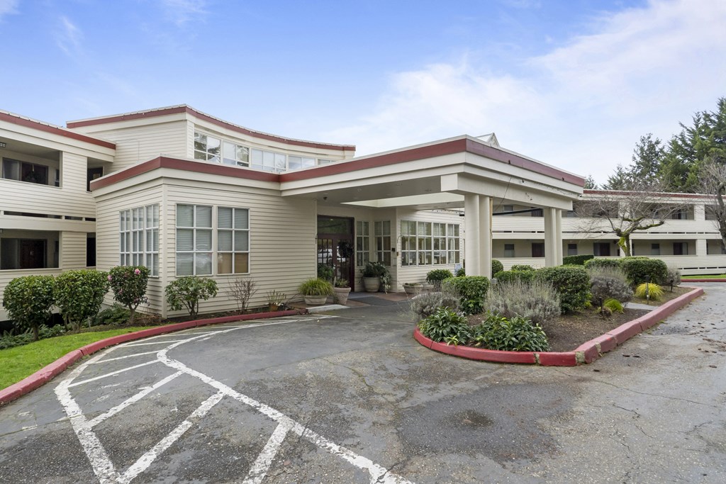 the exterior of a hotel with a parking lot and a building