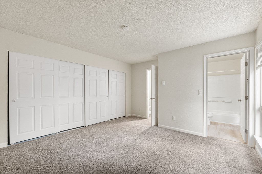the living room of an apartment with white doors and carpet