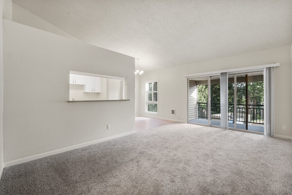 an empty living room with sliding glass doors to a patio