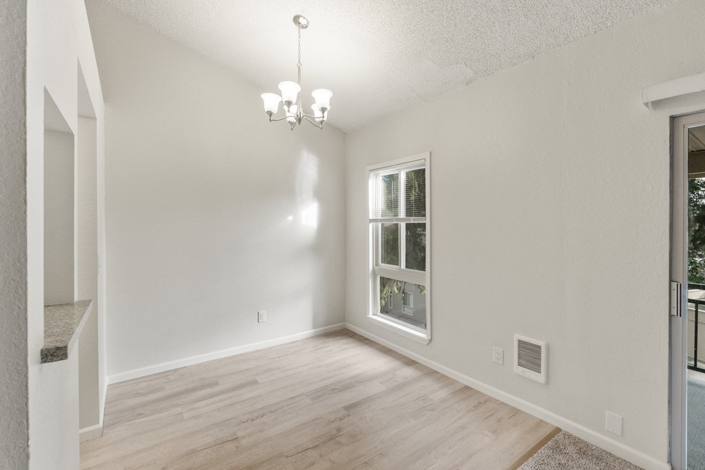 an empty living room with a window and a wooden floor