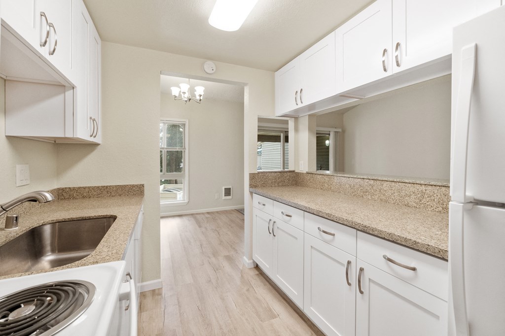 an empty kitchen with white cabinets and granite counter tops
