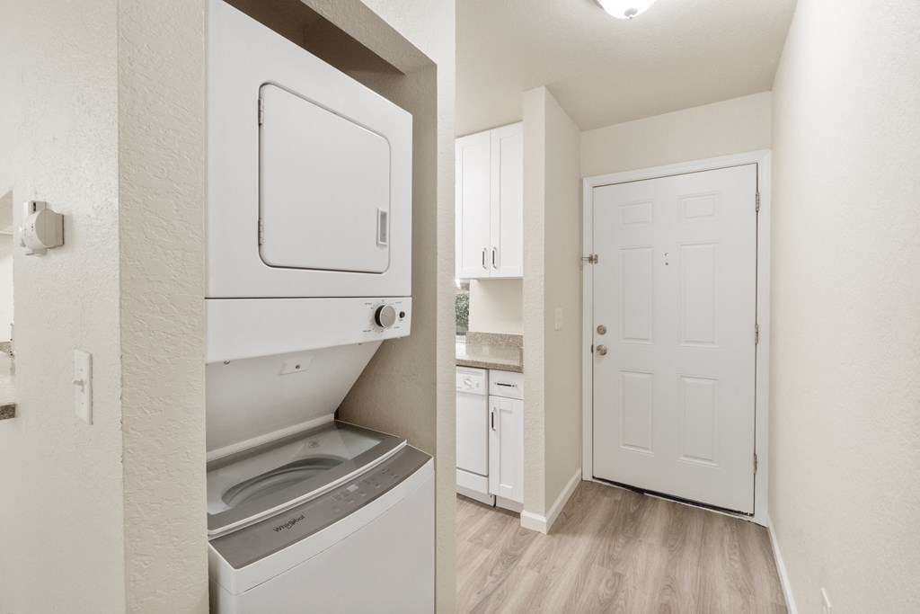 a renovated kitchen with white cabinets and a white door and a washer and dry