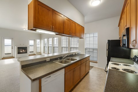 A kitchen with brown cabinets and a black refrigerator.