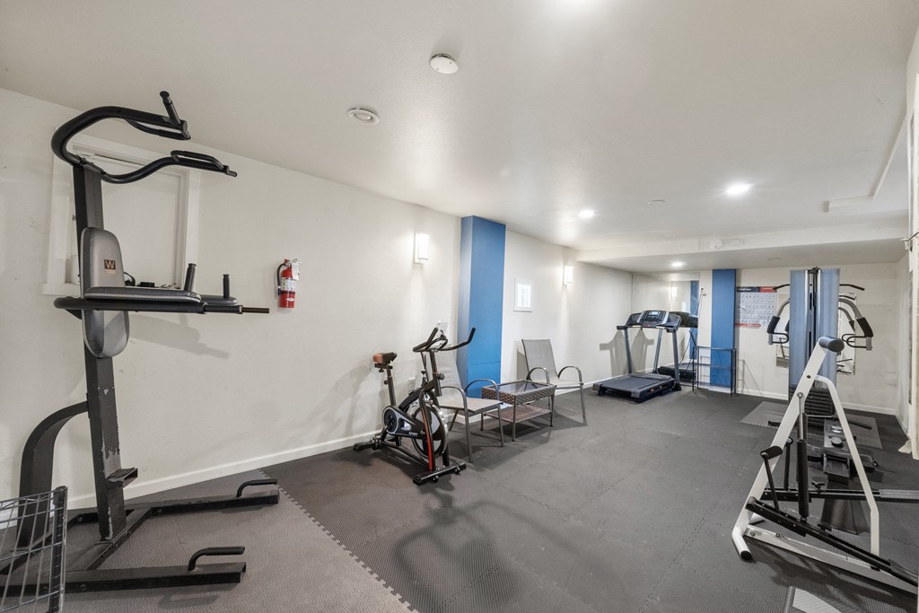 a gym with weights and exercise equipment in a room with white walls