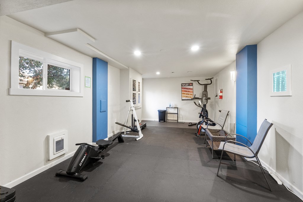 a gym with treadmills and exercise equipment in a room with a window