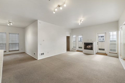 A spacious living room with a fireplace and a carpeted floor.