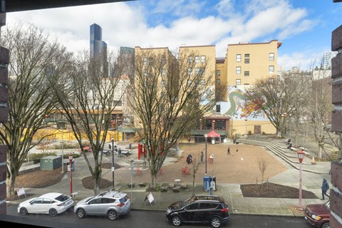 A view of a courtyard with cars and buildings in the background.