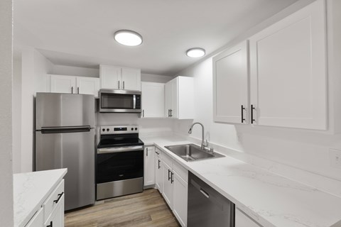 A modern kitchen with white cabinets and stainless steel appliances.