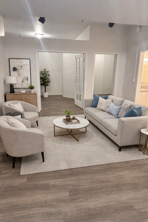 A living room with a grey sofa, a white armchair, a wooden coffee table, and a rug.