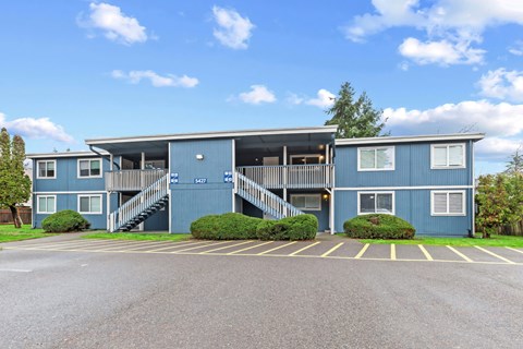 A blue building with a parking lot in front.
