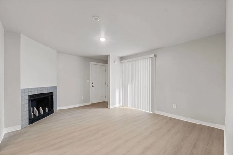 A spacious room with a fireplace and wooden flooring.