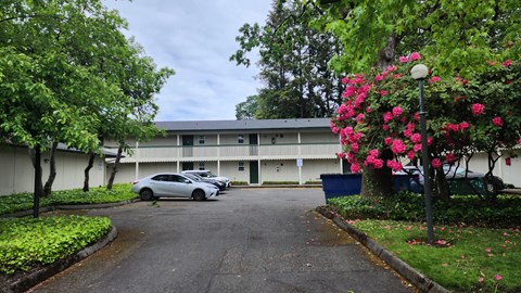 A white building with a grey roof and a car parked in front.